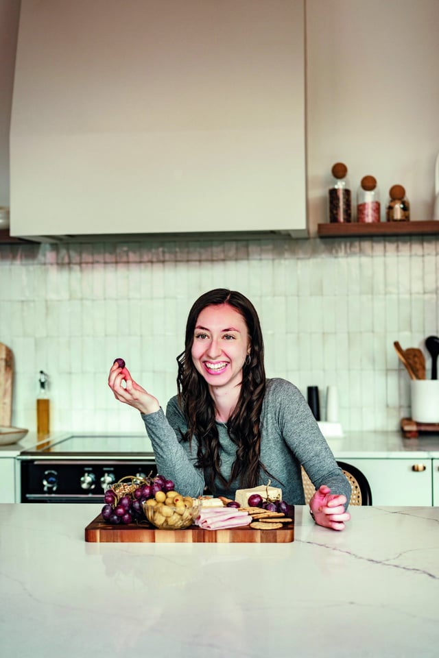 Emilie éclate de rire en tenant un raisin